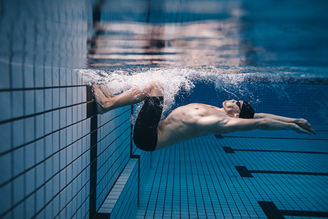 A young man with chronic conditions performing high-intensity interval aquatic training in a swimming pool to improve his physical capacity.  