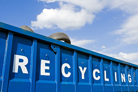 A blue recycling container with car tires. 