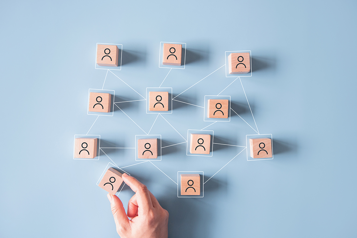 Wooden cubes with people drawn on them are connected by lines, simulating the connection between people. 