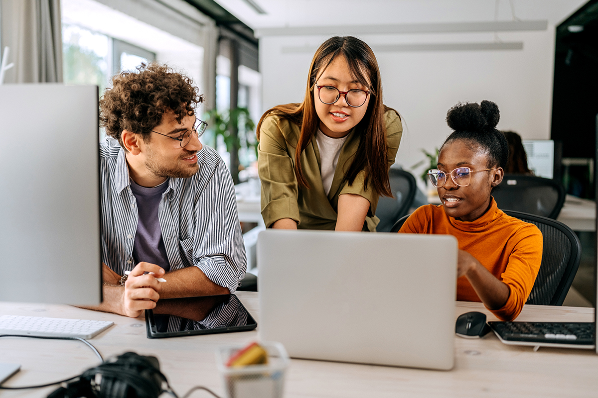 Three young colleagues talk about working in a modern office.
