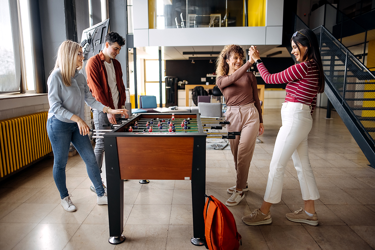 Inclusive design in the company: Employees playing on a foosball table.