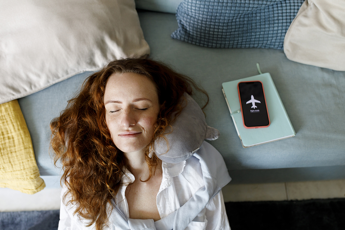 Woman leaning on sofa by phone in airplane mode taking nap at home