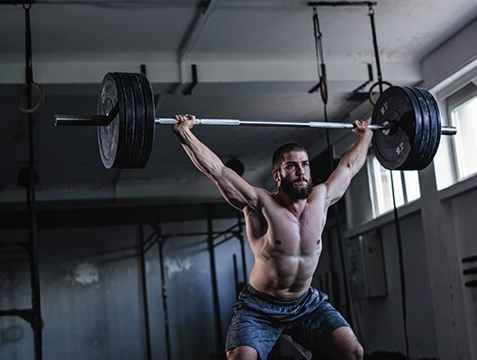 Um atleta a fazer levantamento de pesos para melhorar a sua força muscular. Um atleta a fazer levantamento de pesos para melhorar a sua força muscular.
