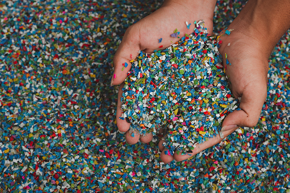 reverse logistics - image of hands holding transparent white plastic pellets, a raw material for various manufacturing processes.