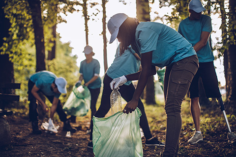 Um grupo de pessoas a recolher plásticos numa floresta para reduzir o impacto do plástico em países vulneráveis.