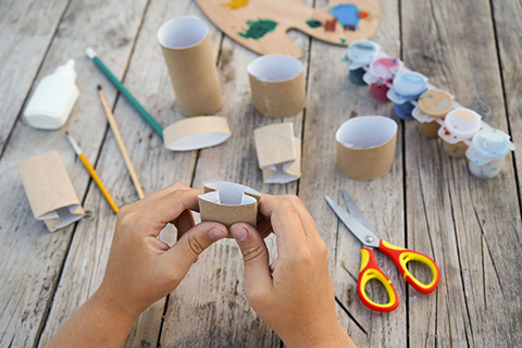 Uma criança faz artesanato com materiais recicláveis na escola, no âmbito do projeto ambiental. 