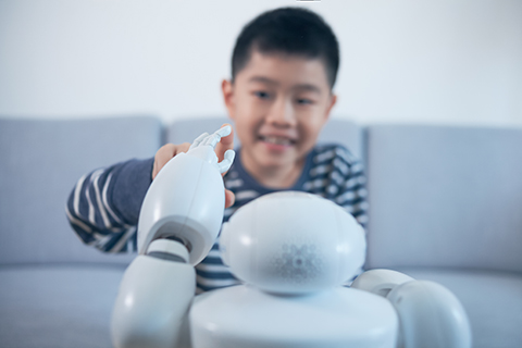 Uma criança a tocar no dedo de um robô. 