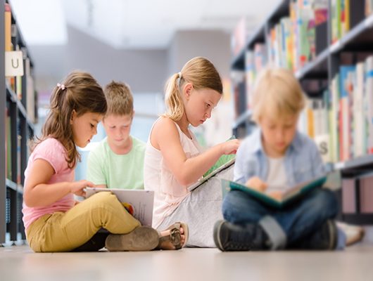 Um grupo de crianças a ler numa biblioteca. 