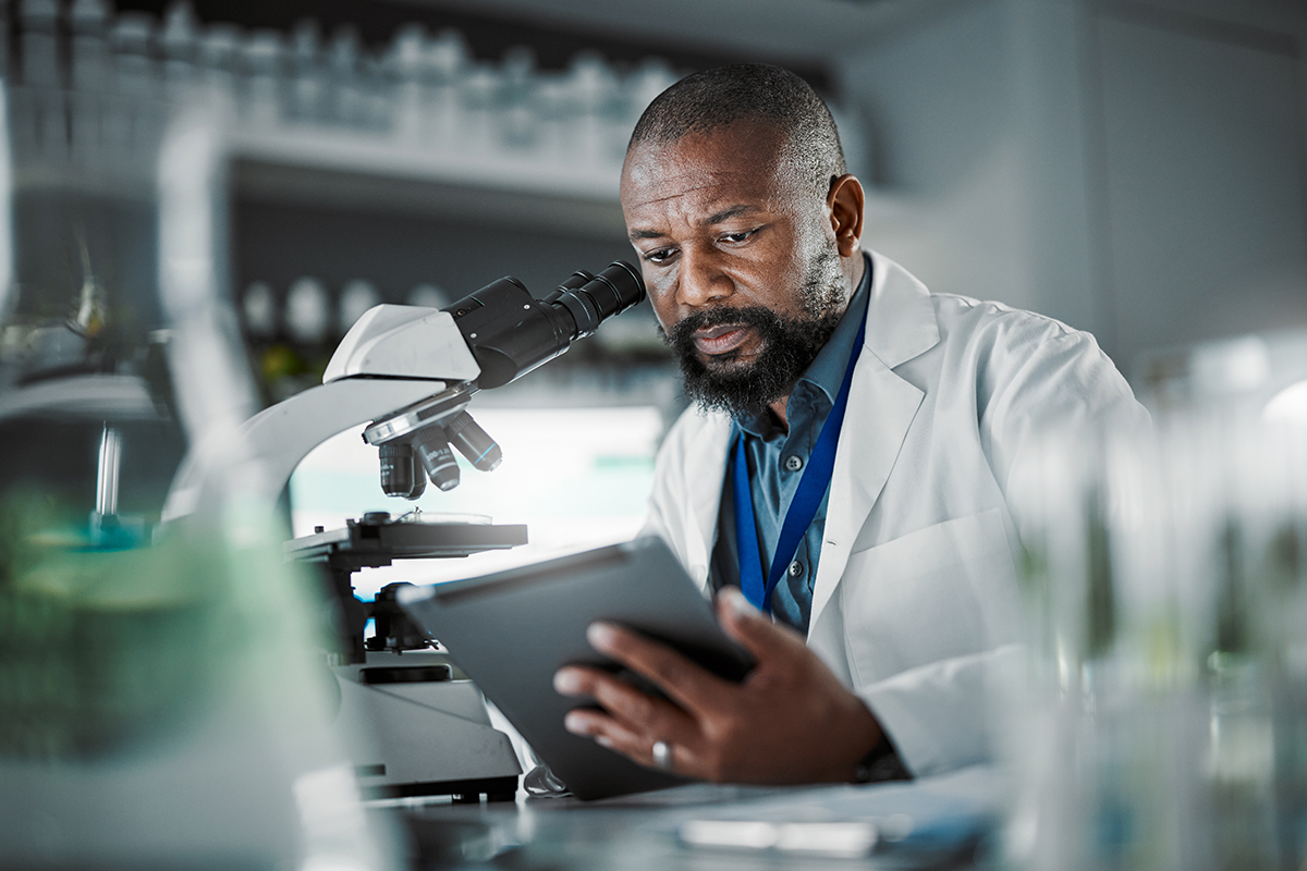 Cientista em seu laboratório, em frente a um microscópio. 
