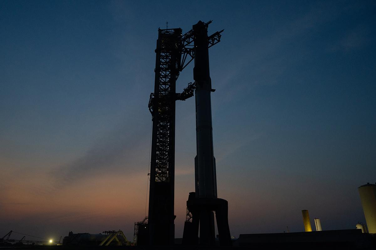 O foguete SpaceX Starship preparado horas antes do lançamento sob o colorido céu noturno.