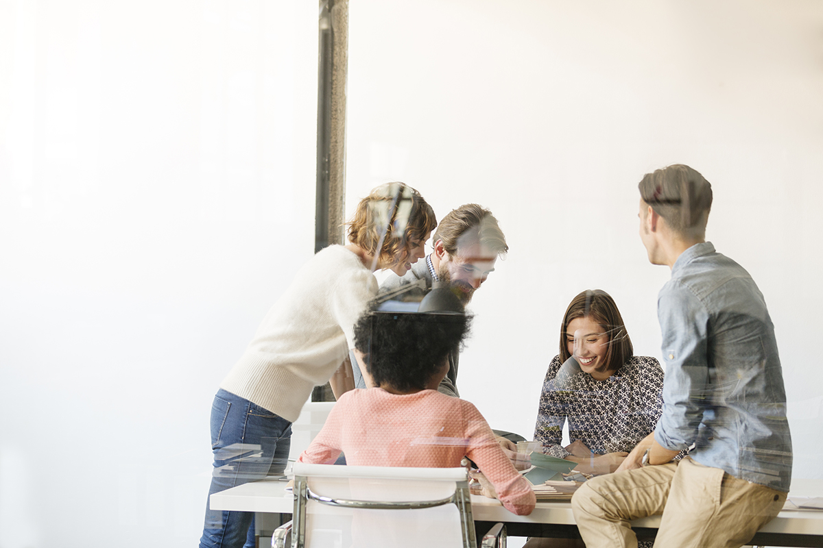 Grupo de colegas de trabalho discutindo em uma mesa de conferência na sala de reuniões.
