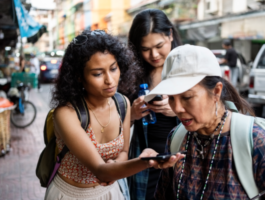 Uma turista segura o telefone para o guia turístico traduzir para ela durante um passeio pela cidade.