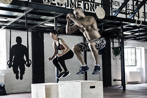 Un hombre y una mujer haciendo entrenamiento intervalado en un gimnasio. 