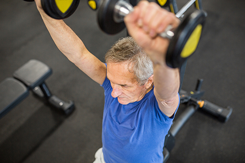 Un adulto mayor haciendo entrenamiento de fuerza para mejorar su salud muscular y física. 