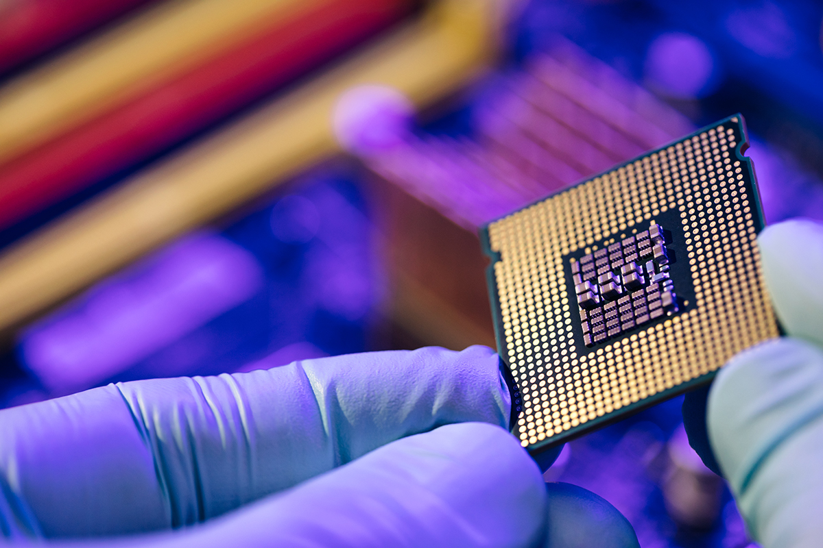 Fabricante sostiene entre sus dedos un chip de computadora. 