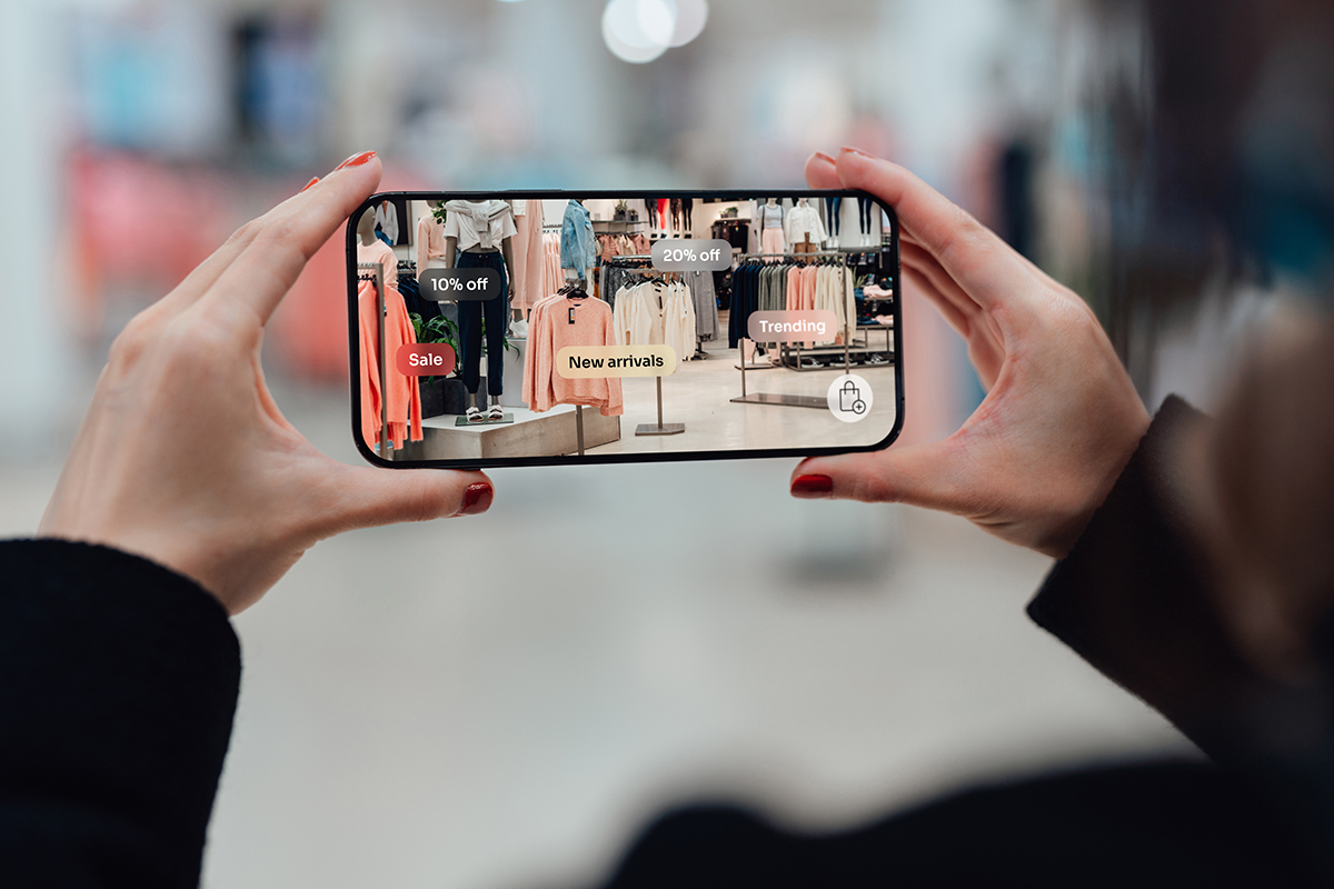 Tendencias de marketing: el uso de la RA. Chica utiliza la cámara de su teléfono para identificar ofertas en una tienda de ropa.